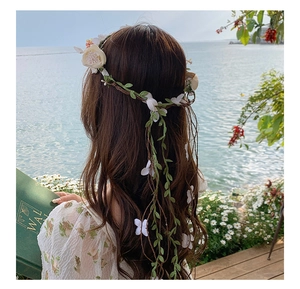 Detail of white flower crown headband with green leaves and butterflies on brown vine