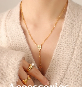 Close-up of gold layered necklace with virgin mary medal, cross pendant and pearl rings