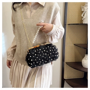 Détail de roses en tissu 3D et perles blanches sur un sac de soirée noir élégant