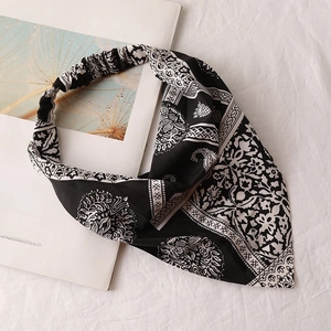Detail view of black and white paisley chiffon headscarf with elastic band on white linen