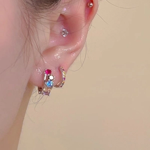 Close-up of rainbow cubic zirconia hoop earring set on ear with golden metal finish