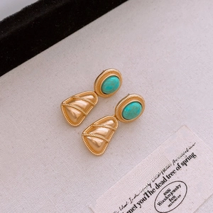 Macro view of vintage gold earrings with turquoise stones and fan-shaped relief detail