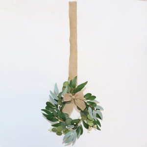Detail of faux greenery wreath with a burlap bow and extra long hanging rope for decor