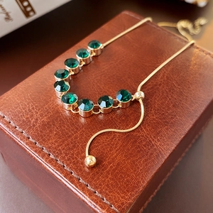Dettaglio della collana placcata oro con zirconi verde smeraldo su portagioie in pelle