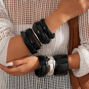 Close-up of stacked resin bangle set in black finish and metallic silver geometric design