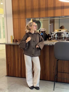 Veste en tricot à carreaux marron pour femme avec revers et boutons dans un café chic