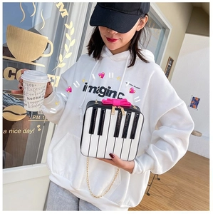 Detail of creative piano keyboard square bag with pink bow and gold chain strap