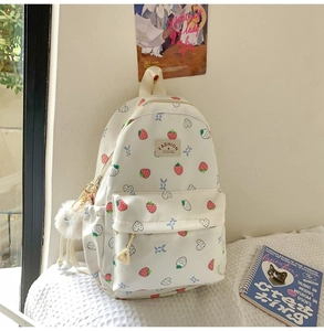 Detail of cute strawberry print backpack with plush pendant and side pockets