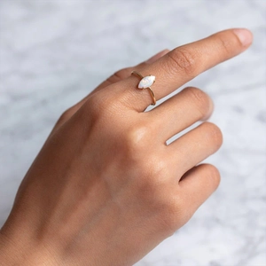 Close-up of a marquise-cut opal ring on a gold band worn on a model's hand