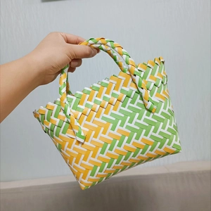 Detail of colorful hand-woven basket bag in green yellow and white plastic weave
