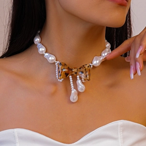 Baroque pearl necklace with leopard print bow and fringe pendant worn by a model