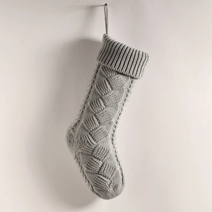 Detailed view of grey knitted Christmas stocking featuring classic cable and diamond patterns