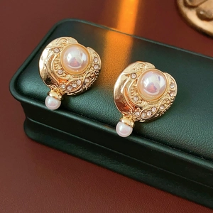 Gros plan de boucles d'oreilles vintage dorées avec perles et strass sur un écrin