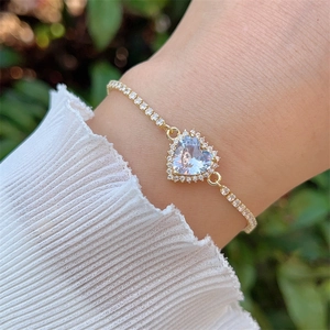 Detailed view of an 18K gold plated heart bracelet with zircon on a woman wrist
