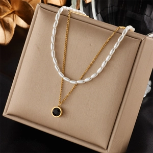 Double-layered gold chain necklace with white pearls and a black round pendant charm