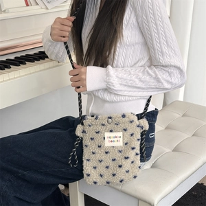 Detail of plush crossbody bag featuring heart patterns and woven shoulder strap