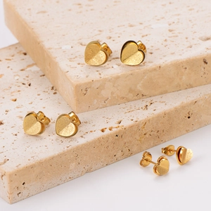 Chic double-layer matte heart stud earrings in gold finish on stone background