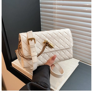 Detailed close-up of white woven leather texture and elegant gold knot clasp of the bag