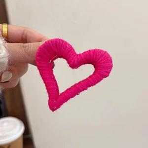 Detail shot of a pink plush heart hair claw clip wrapped in soft wool yarn material