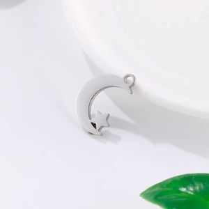 Polished silver stainless steel crescent moon pendant with star cutout on ceramic plate