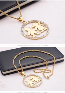 Détail d'un collier chaîne torsadée dorée avec pendentif garçon et fille serti de diamants