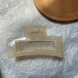 Detailed view of the hollow rectangular beige jelly hair claw clip on white textured paper