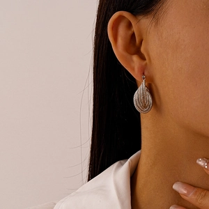 Detail view of silver teardrop earrings with a unique spiral multi-layer texture on the model