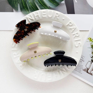 French style acetate hair claws with gold letter B in tortoise shell and cream colors