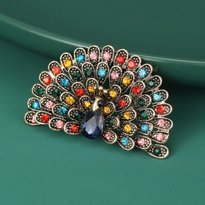 Detailed close-up of a golden peacock brooch featuring vibrant multi-colored rhinestones