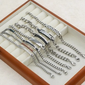 Various stainless steel Cuban and box chain ID bracelets with engraved tags in a display box