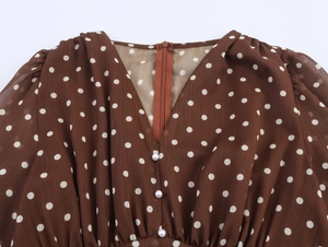 Détail du col en V avec boutons en perles sur la robe en mousseline marron à pois