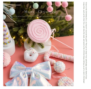 Pink glitter bows and beaded lollipop ornaments decorating a warm lit Christmas tree