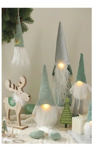 Close-up of glowing sage green Christmas gnomes and wooden reindeer holiday decor