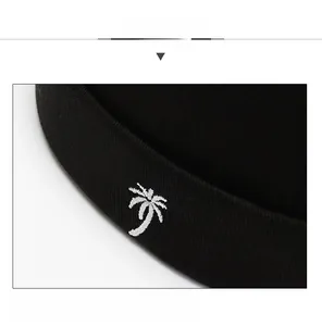Close-up of white palm tree embroidery on a black knit docker cap with fine textures