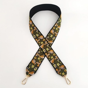 Detailed view of woven floral embroidery bag strap with gold metal rotating clasps