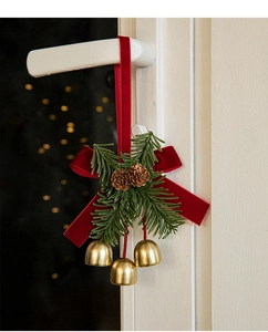 Christmas door hanger with red velvet bow, pine cones, and three gold bells decoration