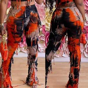 Dettaglio dei pantaloni in maglia tie-dye con design traforato a nappe e bordi sfrangiati