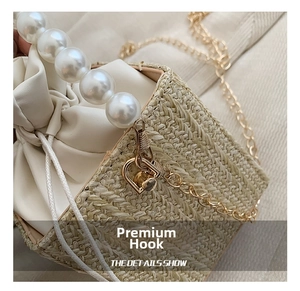 Close-up of woven handbag showing pearl strap and gold metal hook details