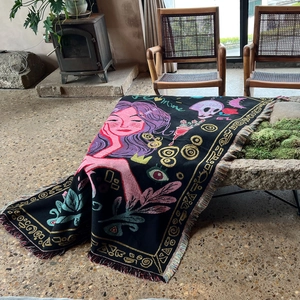 Detail of woven artistic blanket with colorful tassels draped on a stone ledge