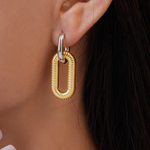 Close-up of interlocking silver and gold earrings with refined spiral texture detail