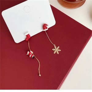 Gros plan de boucles d'oreilles de Noël asymétriques avec Père Noël, bottes et flocons