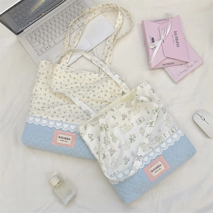 Detailed close-up of quilted floral tote bag with lace trim and brand label tag