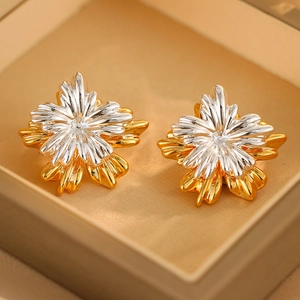 Macro shot of two-tone flower stud earrings with gold and silver metal petals in a box