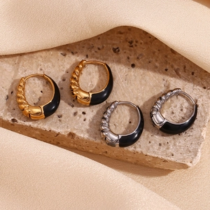 Detail of twist texture and black enamel drip on gold and silver pear-shaped hoop earrings