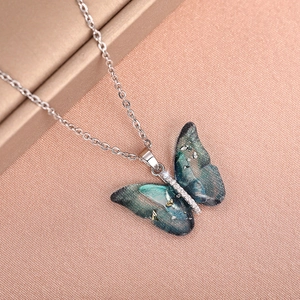 Close-up of butterfly pendant with teal gradient wings and shimmering diamond accents