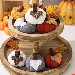 Detail of six knit fabric pumpkins in white gray and brown on a tiered wooden tray