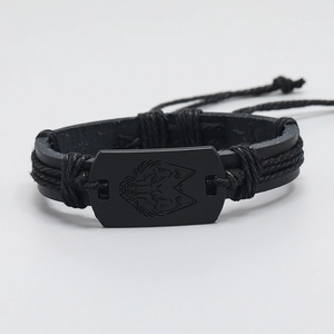 Detail of multi-layer braided black leather bracelet with carved metal wolf head charm