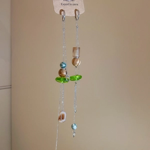 Detail of vintage bohemian earrings featuring long silver chains and green resin beads