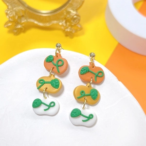 Detailed view of layered pumpkin earrings in orange and white polymer clay material
