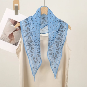 Detail of blue paisley pattern scarf hanging on a wooden hanger with a beige vest